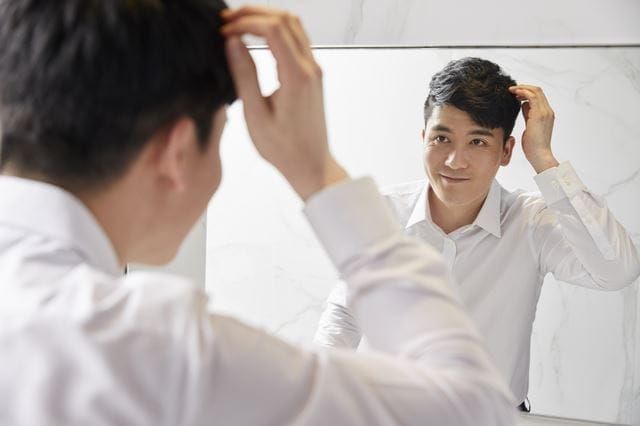 鏡で髪をチェックする男性
